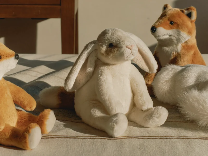 Illustration de peluches douces en coton et lin réunies sur une couverture tissée